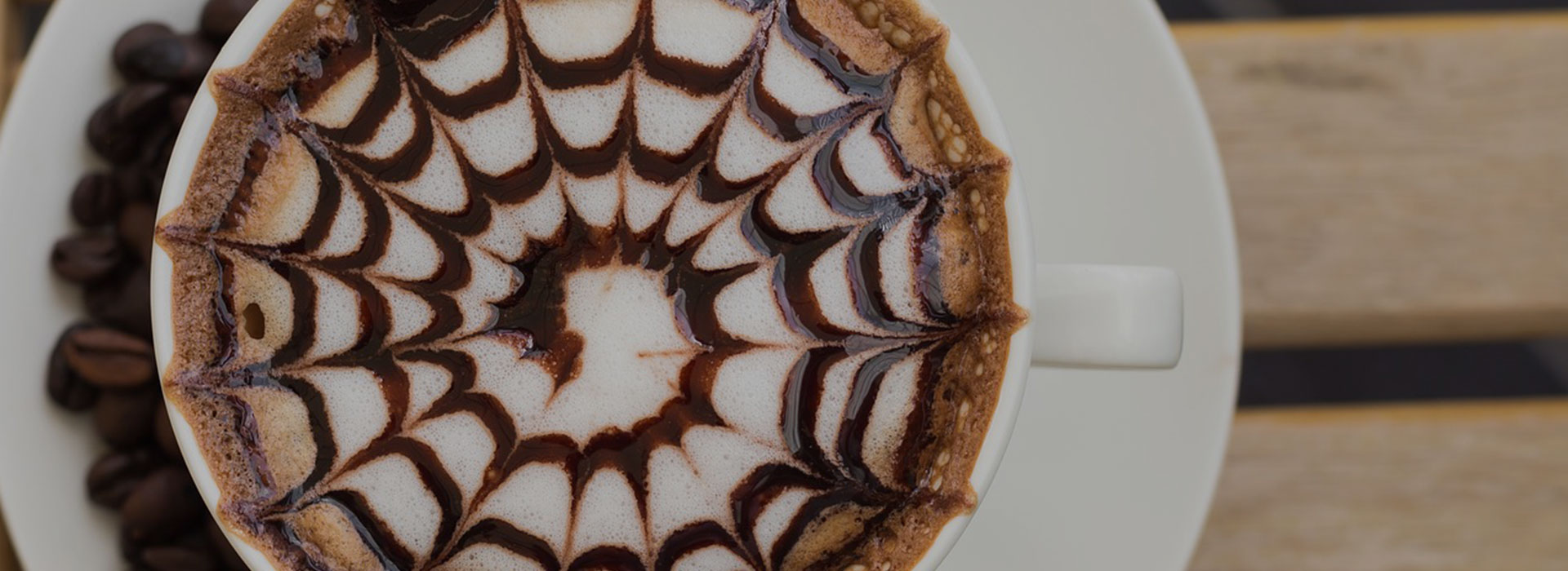 Fotografía detallada de una taza de café con una forma de espiral dibujada en la espuma. Vista desde arriba.