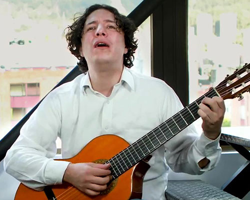 Fotografía de José David tocando la guitarra en el video de Ramona, canción de su autoría.