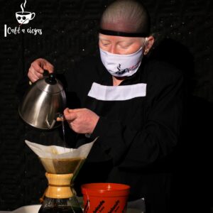 Fotografía de Jaqueline, miembro de Café a Ciegas, preparando café en la chemex